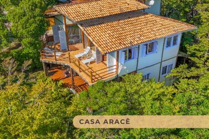 Fachada da Casa Aracê em Ilhabela, com design que integra madeira, vidro e vegetação.